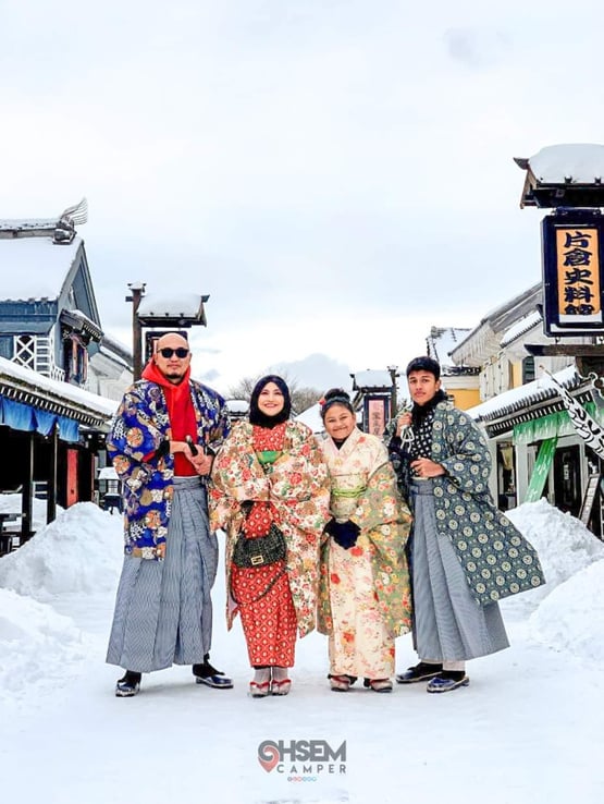 Hokkaido, Japan - three people dressed in traditional japanese clothing (samurai and kimono) pose for a picture in the snow at Date Jidai Village