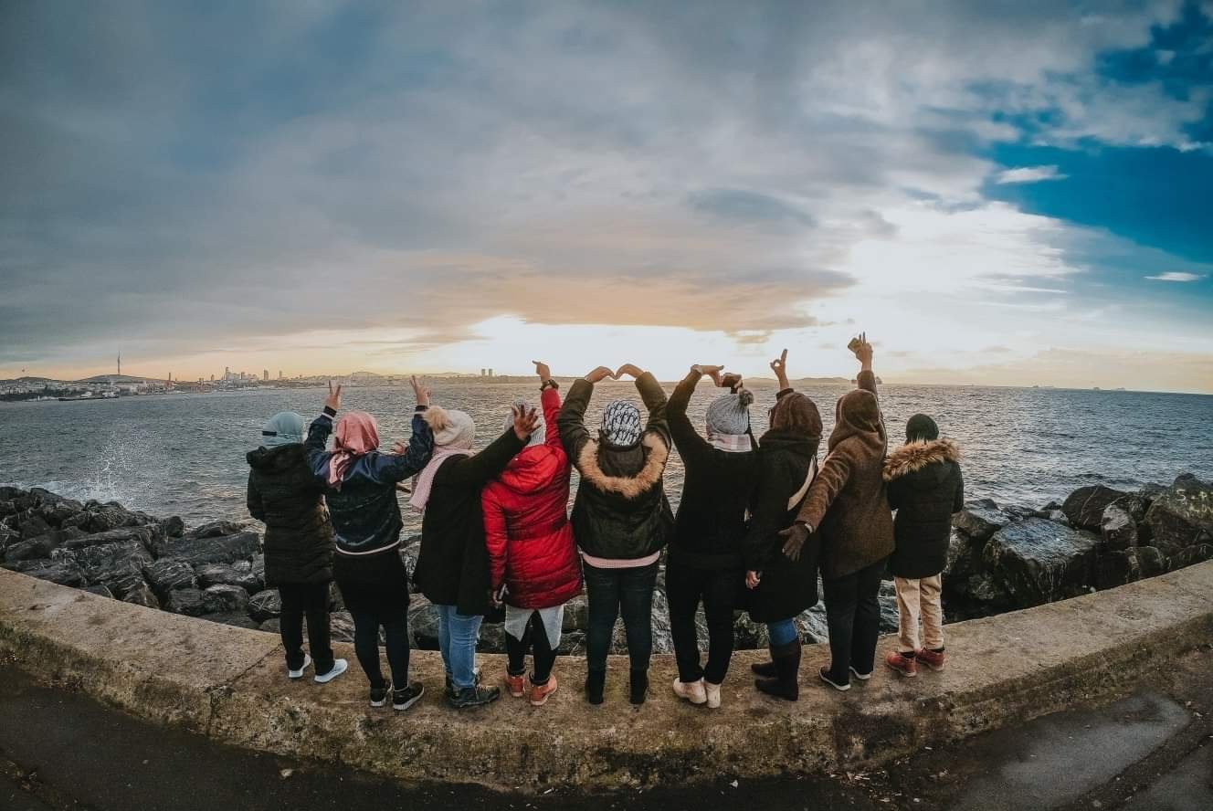 Istanbul, Turkiye - a group of people standing in front of the Bosphorus with their hands in the air OOTD