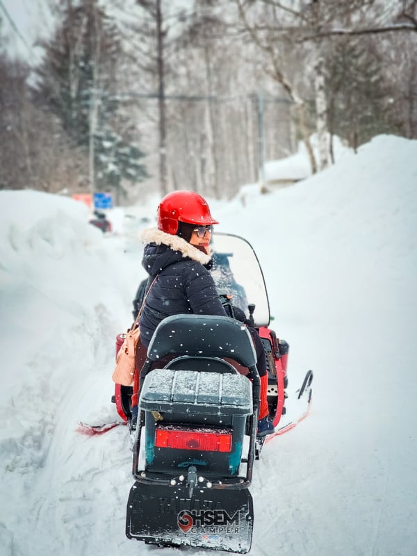 Hokkaido, Japan - a person riding on the back of a snowmobile during winter time at North Safari Sapporo