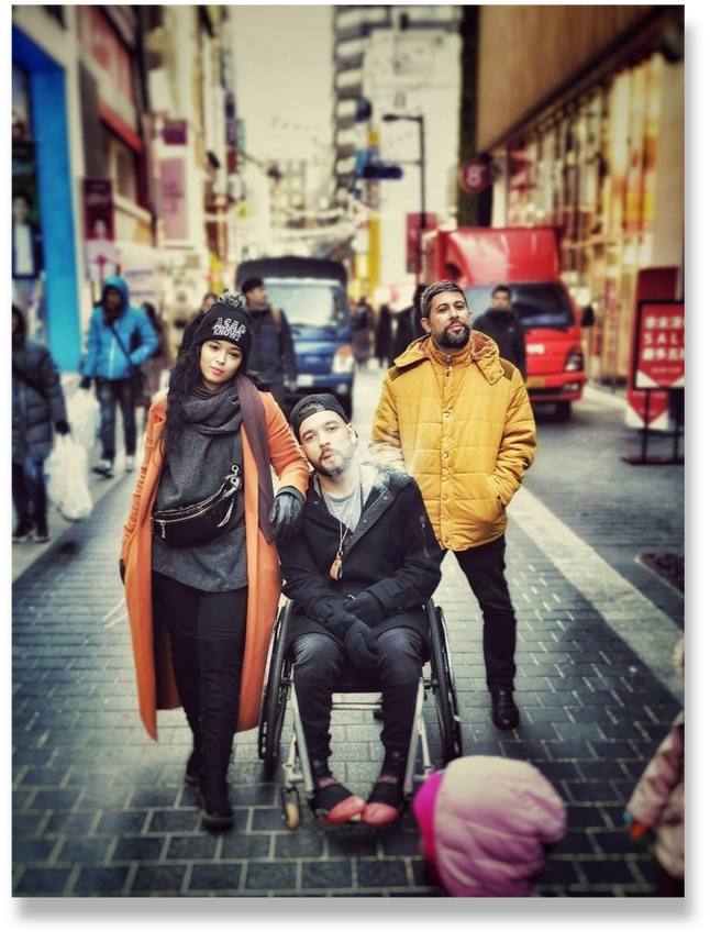 Seoul, South Korea - a person in a wheelchair (Ahmad Maembong) with siblings (Chacha and Mukhlas Maembong) standing next to them in Myeongdong 