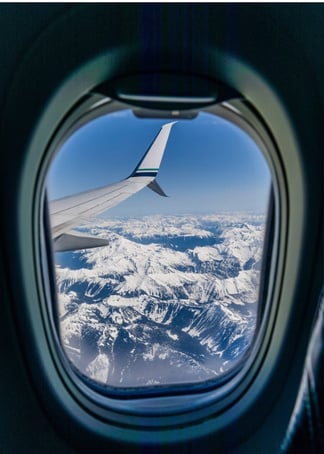 an airplane window with a view of snow capped mountains. Air Asia, Turkish Airlines,  Malaysian Airlines,  Japan Airlines, International Airport.