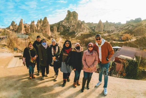 a group of people posing for a photo in front of some rock formations during Red-tour in "Love Valley" Cappadocia,  Turkiye